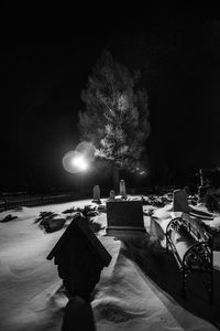 Man by illuminated tree against sky at night