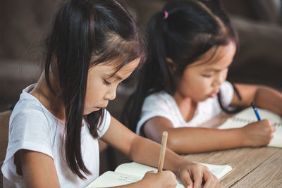 Sisters studying on table at home