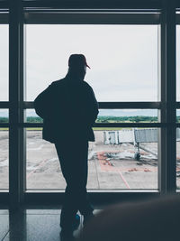 Rear view of man looking through window