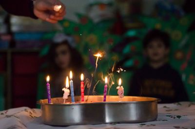 Lit candles on cake in container