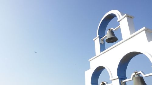 Low angle view of crane and building against clear blue sky