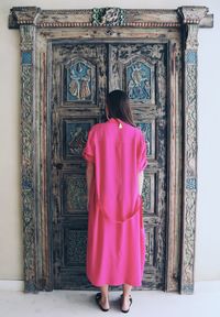 Rear view of woman standing against door of building