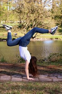 Full length of woman doing handstand on footpath