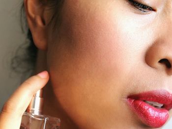 Cropped image of beautiful woman applying perfume