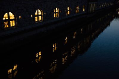 Bridge over river against illuminated buildings at night