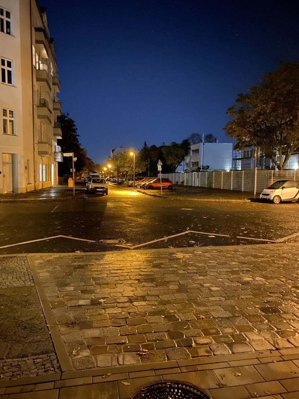 WET STREET BY ILLUMINATED BUILDINGS IN CITY