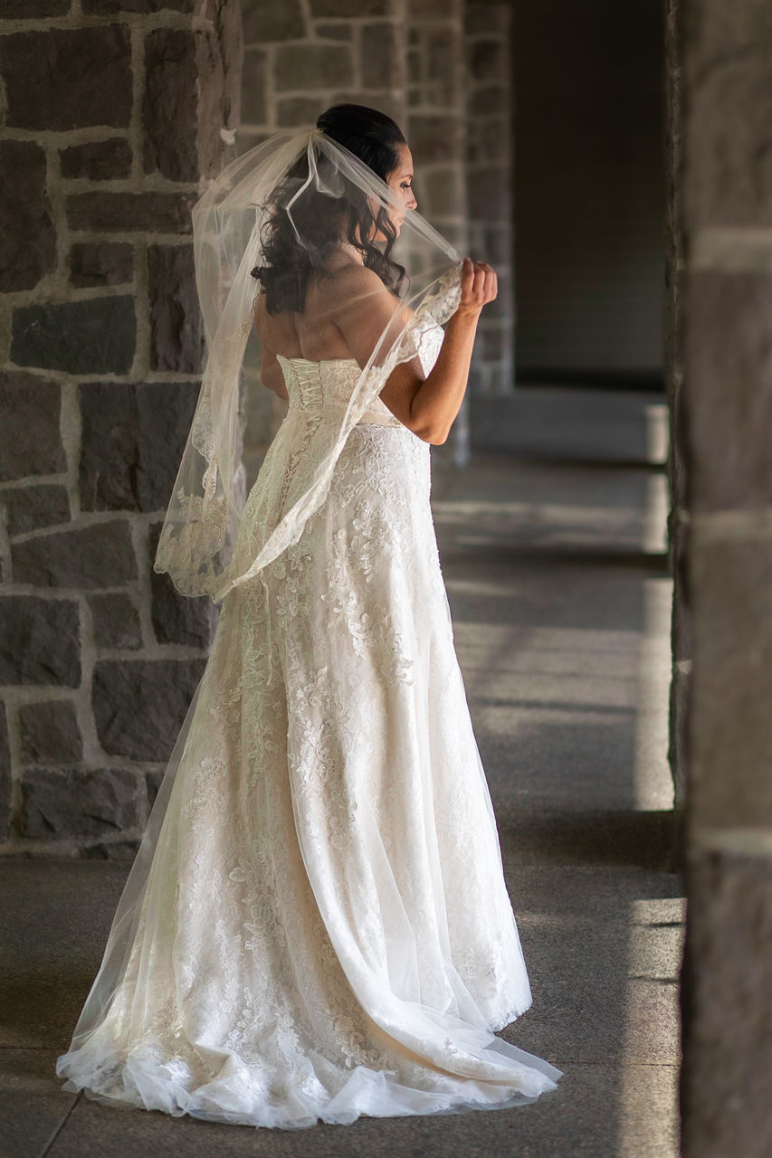 women, wedding, real people, one person, wedding dress, standing, newlywed, celebration, bride, event, full length, fashion, side view, adult, white color, lifestyles, young adult, life events, built structure, veil