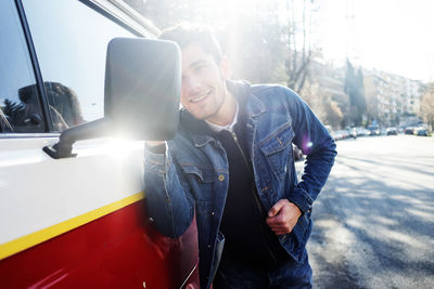 Smiling man looking in side view mirror of van