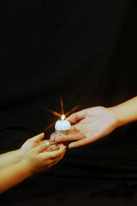 Close-up of hand holding lit candle