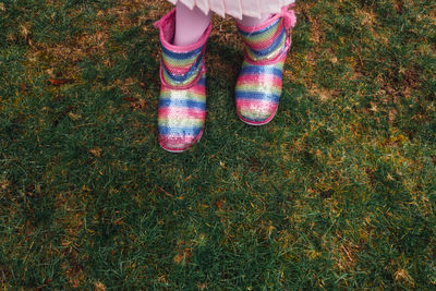 Pink, blue, yellow sequin sparkly boots on young girl, child, kid in dress on grass