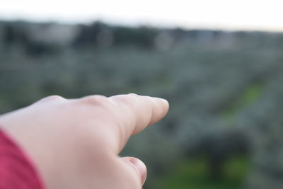 Close-up of human hand against sky