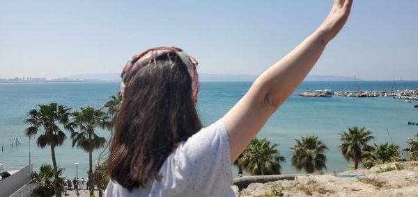 Rear view of woman at beach against sky