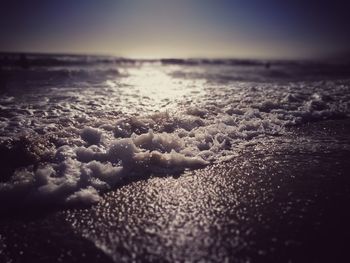 Close-up of wet beach against sky during sunset