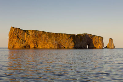 Rock formations by sea against clear sky