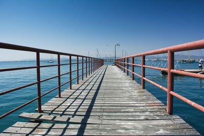 Jetty over sea against clear blue sky