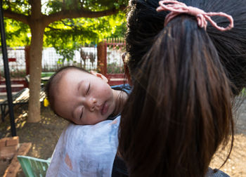 Close-up, half-asian baby asleep on mother's shoulder