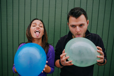 Portrait of smiling young man holding balloons