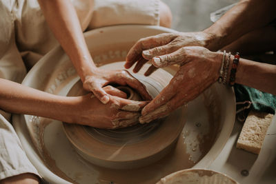 Potter teach teenage girl working with pottery wheel. top view. close up.