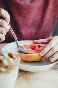 Close-up of hands holding a grapefruit in a bowl
