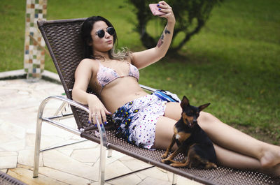 Woman taking selfie while sitting on lounge chair