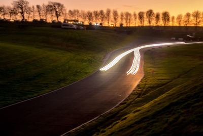 Aerial view of illuminated road against sky at sunset