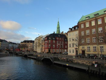 View of buildings by canal against sky in city