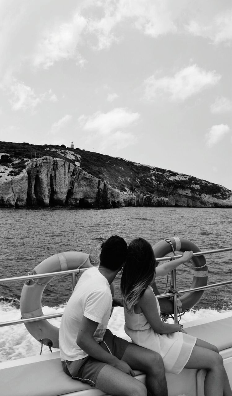 COUPLE SITTING ON BOAT AGAINST SEA