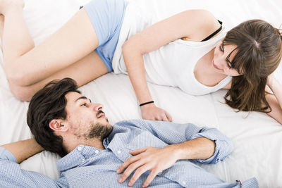 High angle view of couple lying on bed at home