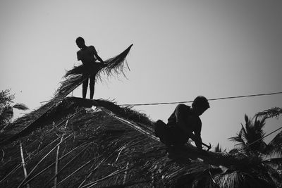 Full length of men fishing net against clear sky