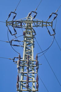 Low angle view of electricity pylon against blue sky