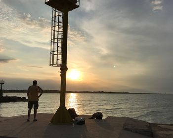 Silhouette man standing on beach against sky during sunset