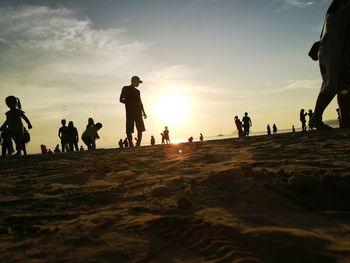 People on beach against sky during sunset