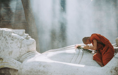 Side view of woman sitting on cross