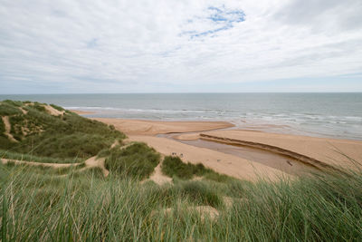 Scenic view of beach against cloudy sky