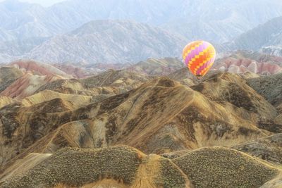 View of hot air balloon flying over mountain