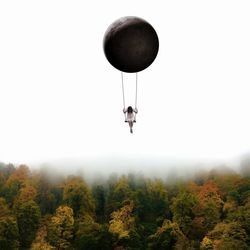 Person paragliding in forest against sky