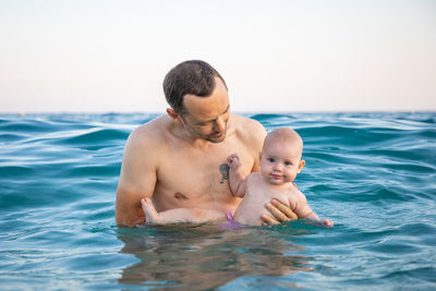 Father and daughter in sea against sky