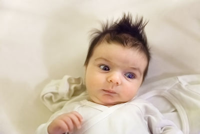 Portrait of cute baby lying on bed