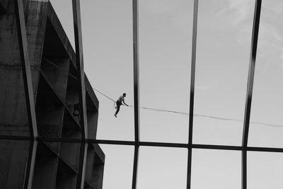 Low angle view of man working on rope against sky