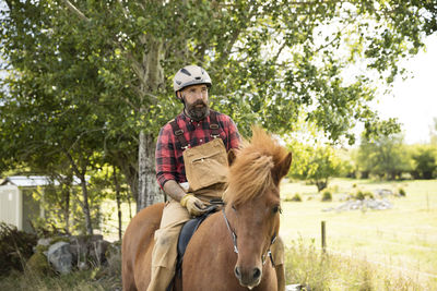 Male farmer in helmet riding horse