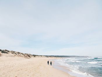 People walking on beach against sky