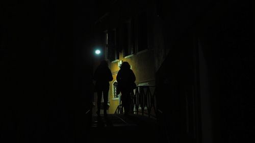 Rear view of silhouette man walking in illuminated building