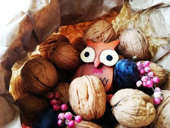 High angle view of walnuts with owl shaped toy in paper