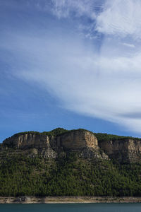 Scenic view of sea by mountain against sky