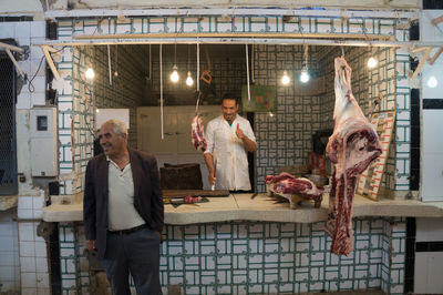 Smiling customer standing by butcher showing thumbs up at shop