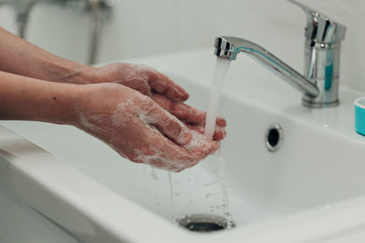 Cropped hand washing hands in sink