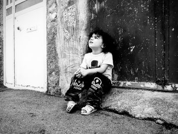 Full length of girl sitting against wall