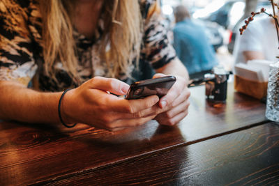 Close-up of woman using smart phone on table