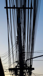 Low angle view of silhouette electricity pylon against sky