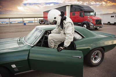 Sportsman sitting in vintage car while preparing for sports race